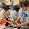 Two Carleton students make empanadas with a seventh grader from Northfield Middle School.